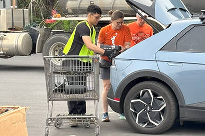 Staff helping upload electronics from a participant's car.